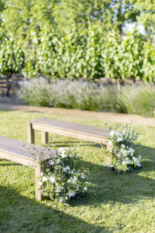 the vineyard close up benches with floral arrangements.